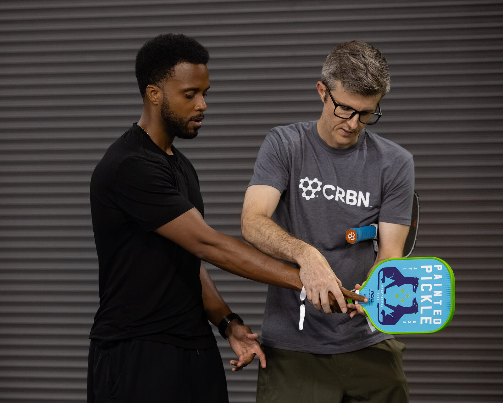 A coach helping a beginner with hand placement on the paddle