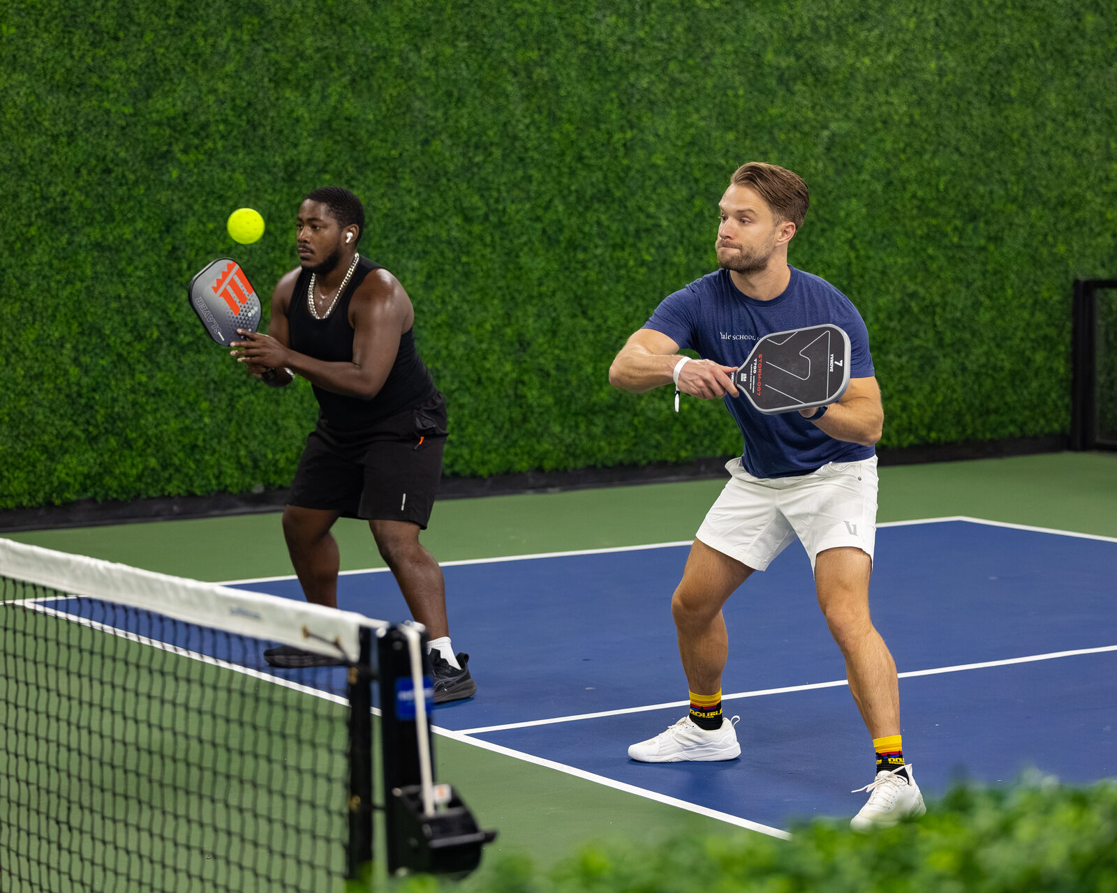 Two players tapping paddles at the net