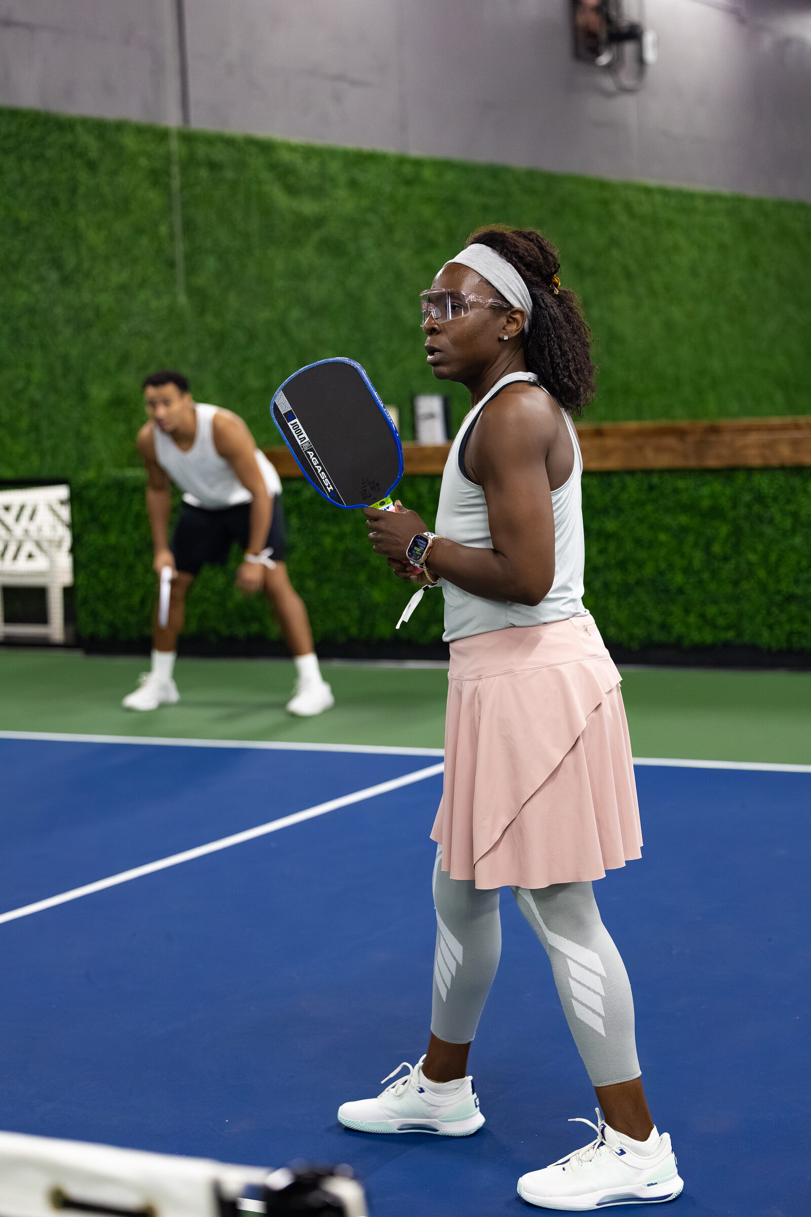 A player mid-rally in a pink skirt and headband